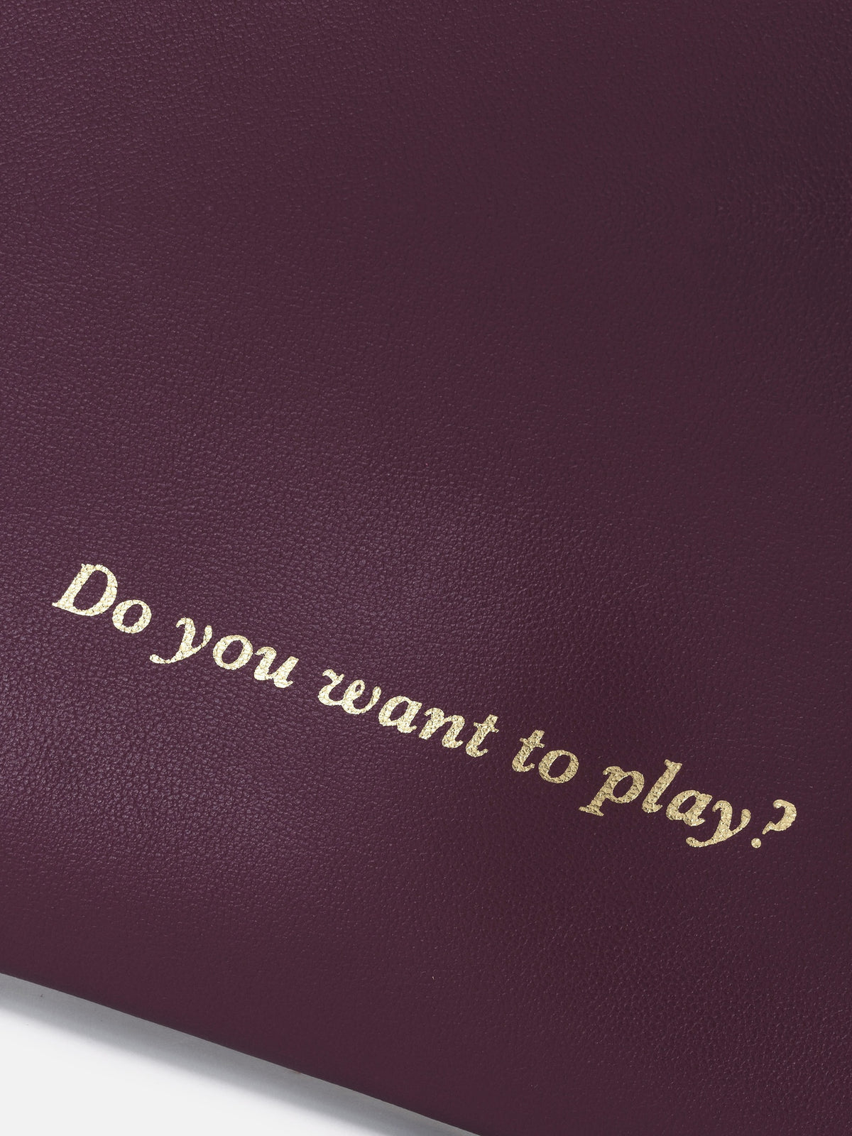 Detalle de "Do you want to play?" grabado en dorado sobre piel burdeos – Mercules Backgammon Club
