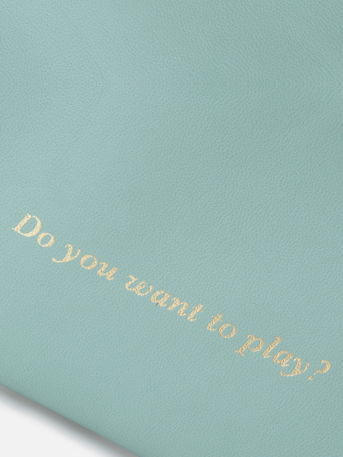 Detalle de "Do you want to play?" grabado en dorado sobre piel turquesa – Mercules Backgammon Club